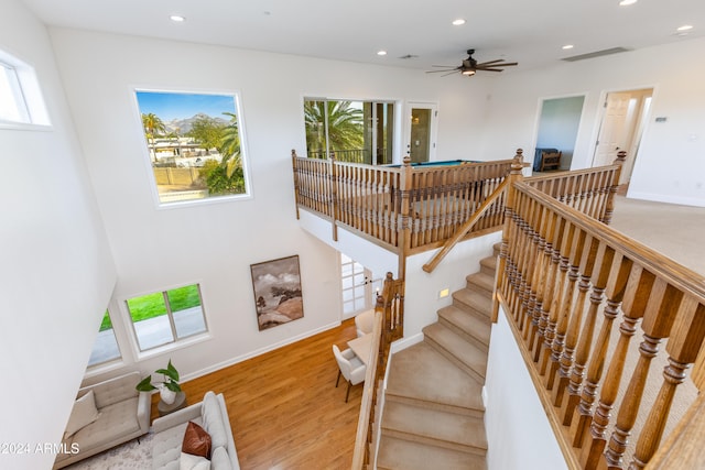 staircase with ceiling fan and wood-type flooring