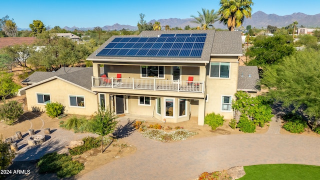 back of house featuring a mountain view, solar panels, a patio, and a balcony