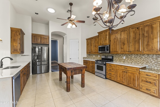 kitchen with sink, hanging light fixtures, tasteful backsplash, light tile patterned flooring, and appliances with stainless steel finishes