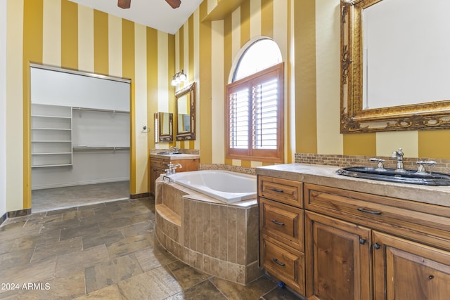 bathroom featuring ceiling fan, vanity, and a relaxing tiled tub