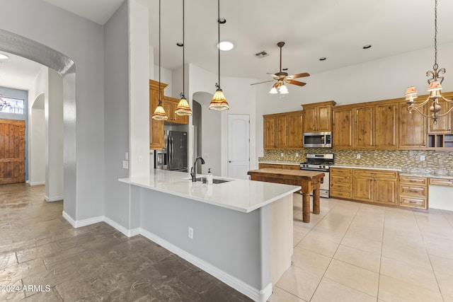 kitchen with decorative backsplash, sink, stainless steel appliances, and hanging light fixtures