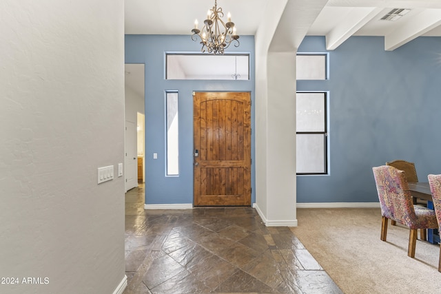 entrance foyer featuring dark colored carpet, beam ceiling, and an inviting chandelier