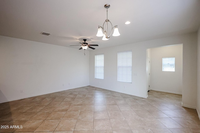 tiled spare room with ceiling fan with notable chandelier