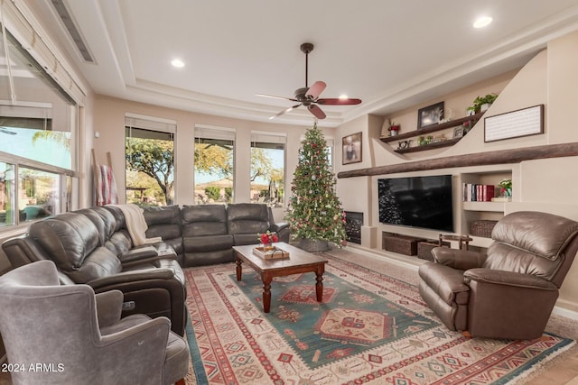 living room with ceiling fan, built in features, and a tray ceiling