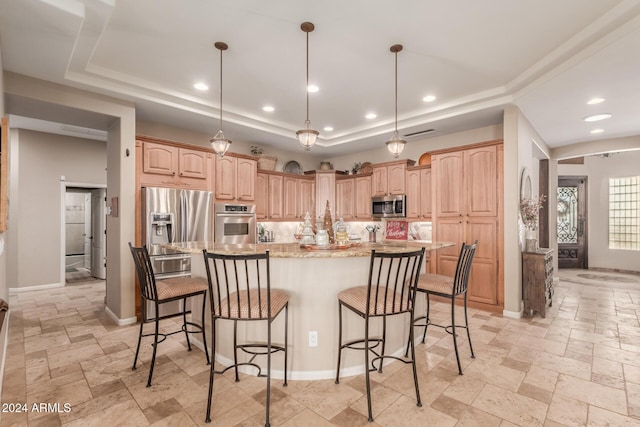 kitchen with light stone countertops, hanging light fixtures, stainless steel appliances, a raised ceiling, and a center island with sink