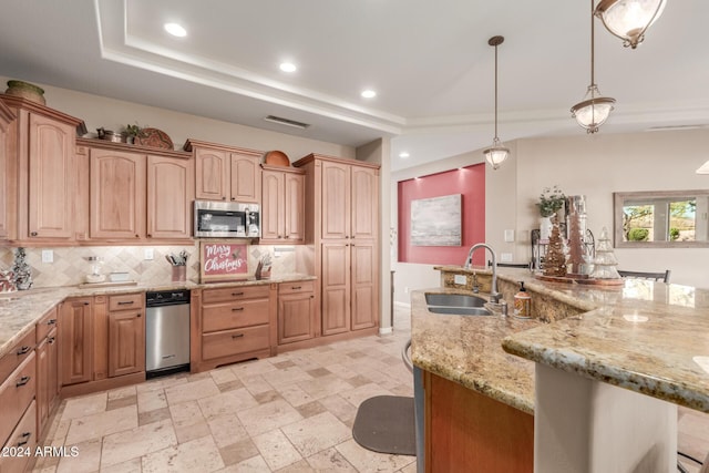 kitchen with light stone countertops, sink, hanging light fixtures, a breakfast bar area, and decorative backsplash