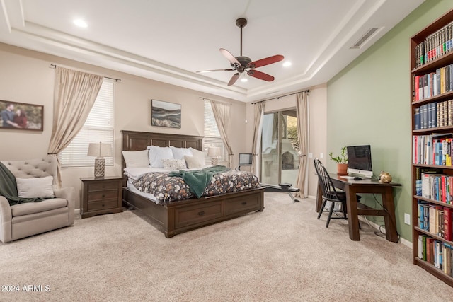 carpeted bedroom with a raised ceiling and ceiling fan