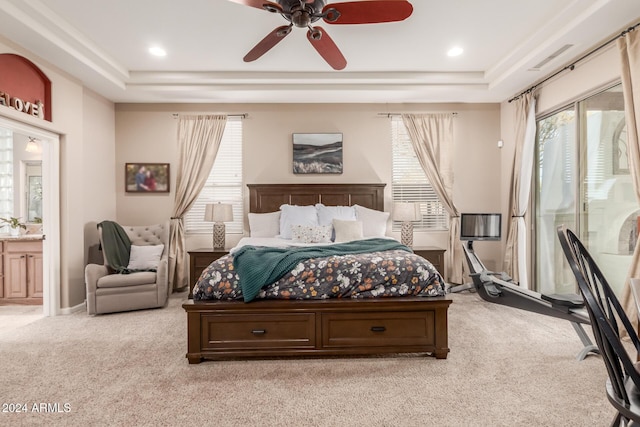 bedroom featuring light carpet, connected bathroom, multiple windows, and ceiling fan