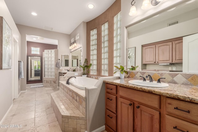 bathroom with tile patterned flooring, vanity, a relaxing tiled tub, and tasteful backsplash