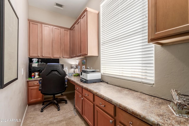 home office featuring built in desk and light carpet