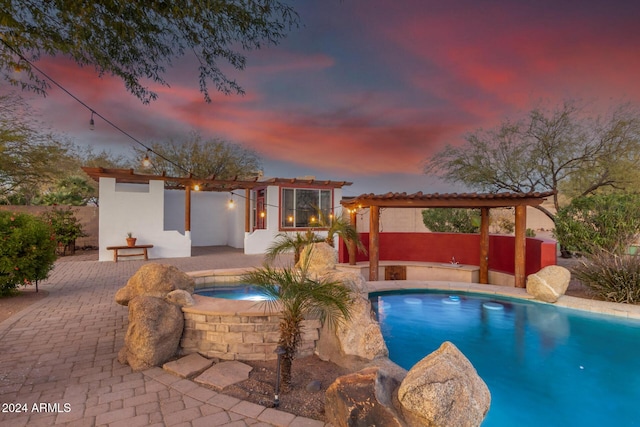 pool at dusk featuring an in ground hot tub and a patio