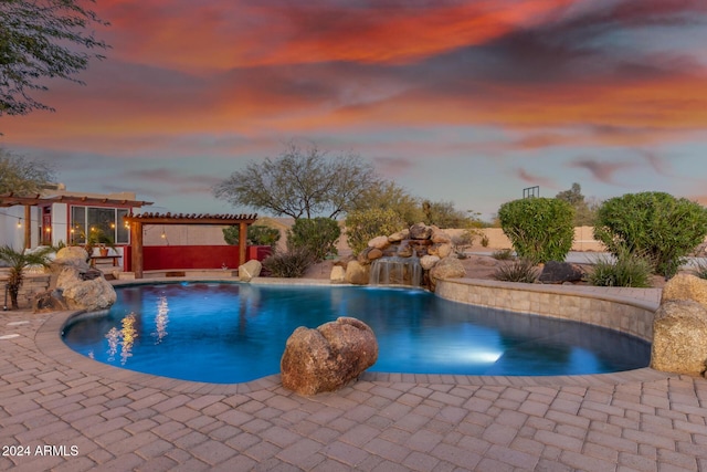 pool at dusk with pool water feature, a pergola, and a patio