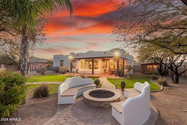 back house at dusk featuring a lawn, a patio area, and an outdoor living space with a fire pit