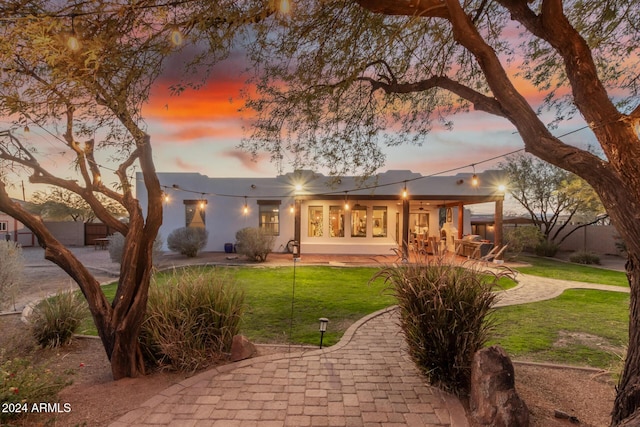 back house at dusk with a yard and a patio area