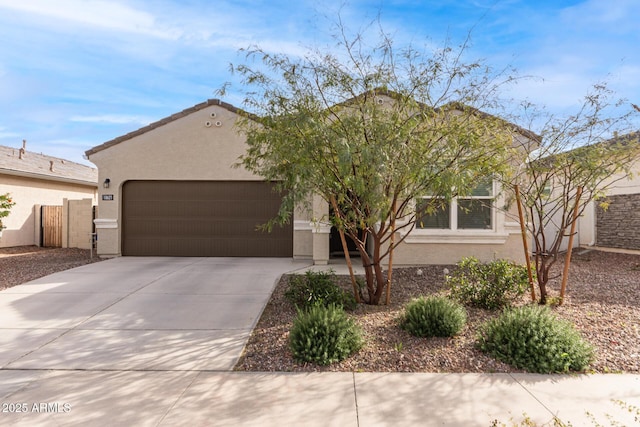 view of front of house featuring an attached garage, fence, concrete driveway, a tiled roof, and stucco siding