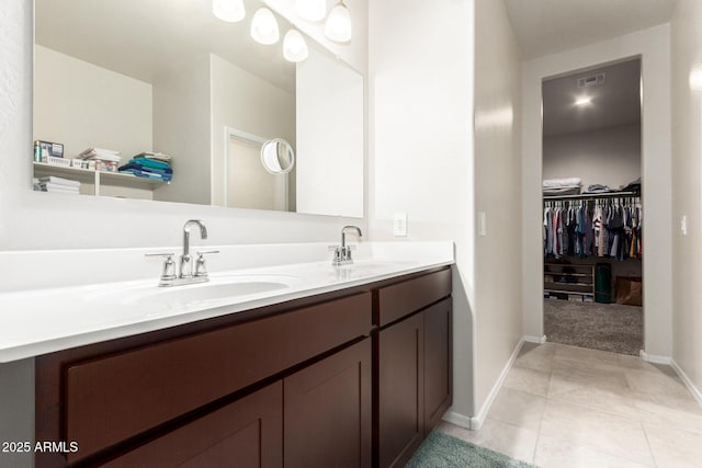 full bath featuring tile patterned flooring, a walk in closet, a sink, and double vanity