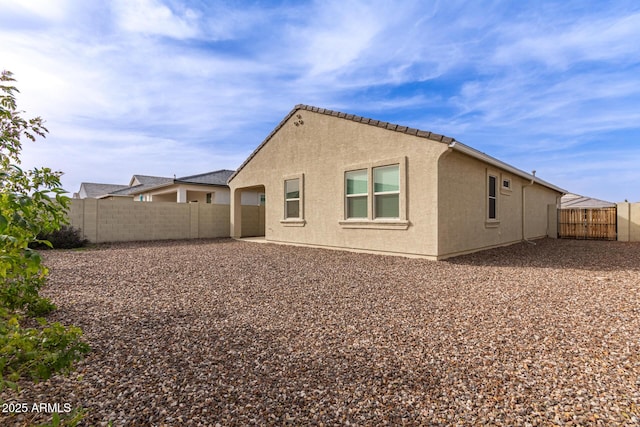 rear view of property featuring a fenced backyard and stucco siding