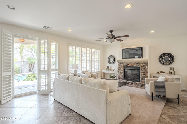 living room featuring light tile patterned floors, a ceiling fan, visible vents, a fireplace, and recessed lighting