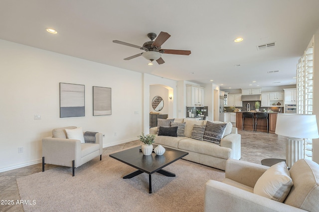 living area featuring baseboards, visible vents, recessed lighting, arched walkways, and ceiling fan