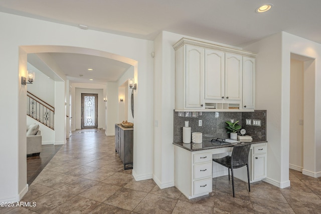 kitchen featuring recessed lighting, decorative backsplash, arched walkways, and baseboards