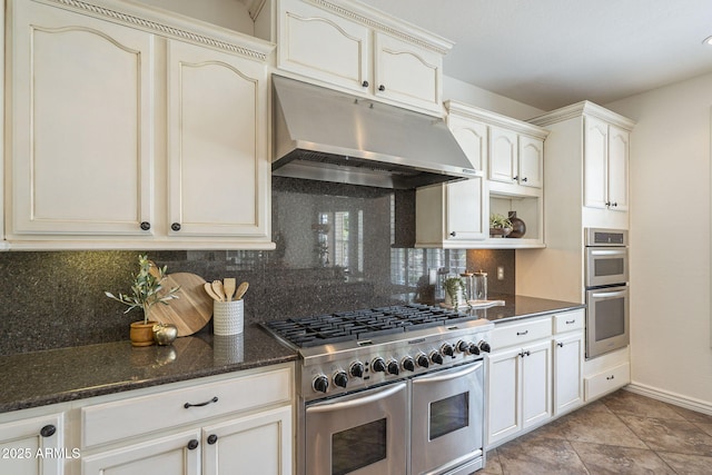 kitchen featuring under cabinet range hood, open shelves, backsplash, stainless steel appliances, and dark stone counters