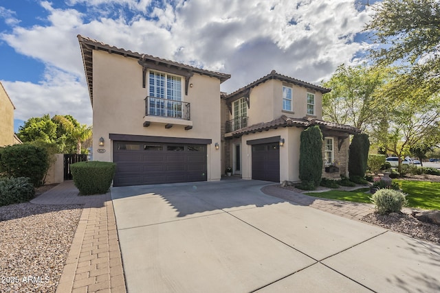 mediterranean / spanish-style home featuring a tile roof, stucco siding, an attached garage, and concrete driveway