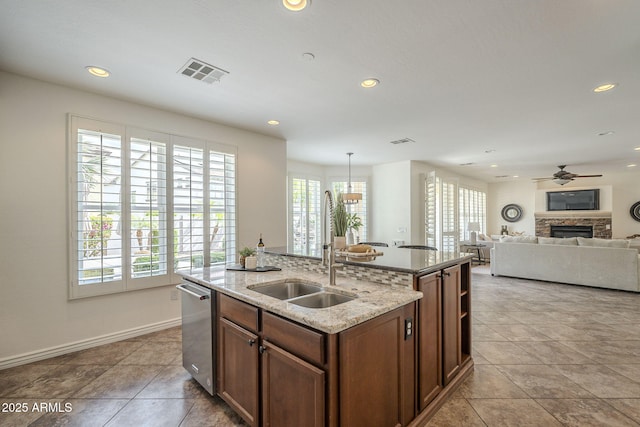 kitchen featuring visible vents, a sink, recessed lighting, a fireplace, and dishwasher