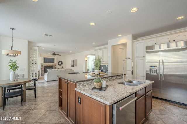 kitchen with visible vents, a center island with sink, a ceiling fan, a sink, and stainless steel appliances