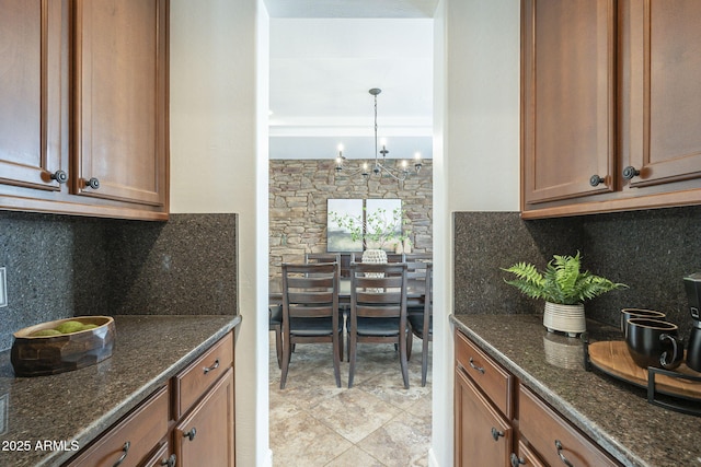 kitchen with dark stone countertops, a notable chandelier, and backsplash