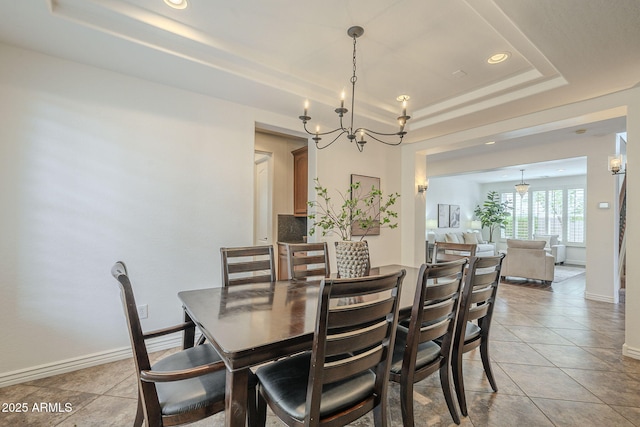 dining room featuring a chandelier, light tile patterned floors, a raised ceiling, and baseboards