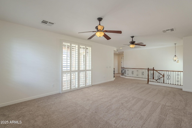 carpeted spare room featuring a ceiling fan, visible vents, and baseboards