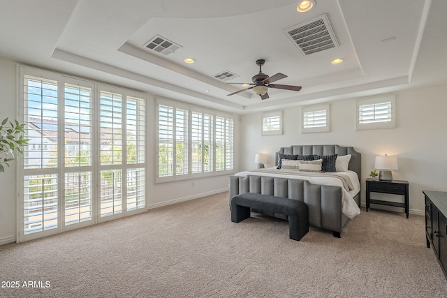 carpeted bedroom with visible vents and a raised ceiling