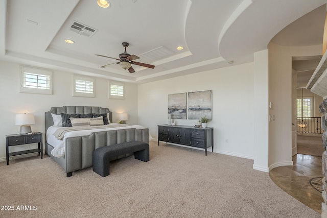 bedroom featuring a tray ceiling, multiple windows, and visible vents