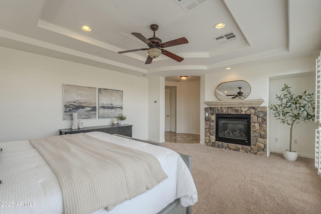 bedroom featuring a tray ceiling, visible vents, and a fireplace