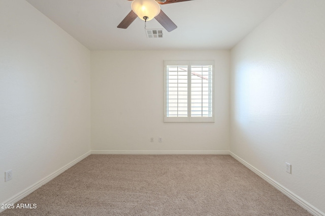 carpeted spare room with visible vents, baseboards, and ceiling fan