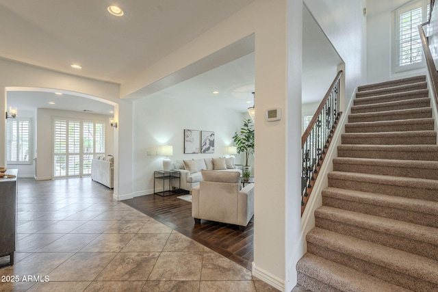 stairs featuring recessed lighting, baseboards, arched walkways, and tile patterned flooring