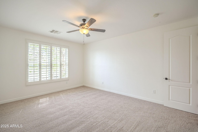 carpeted spare room with visible vents, baseboards, and a ceiling fan