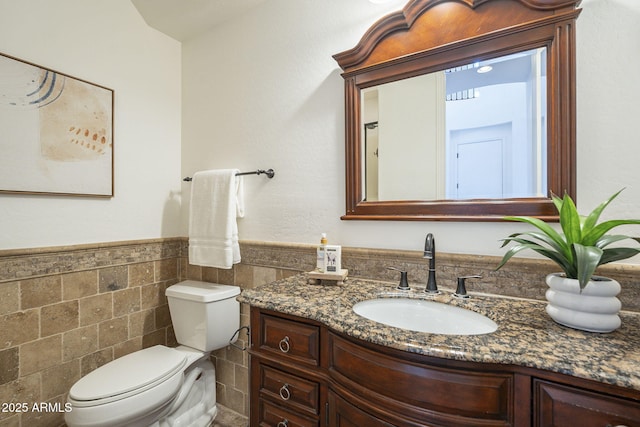 bathroom featuring vanity, tile walls, toilet, and wainscoting