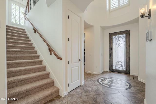 foyer entrance with stairway, baseboards, and light tile patterned flooring