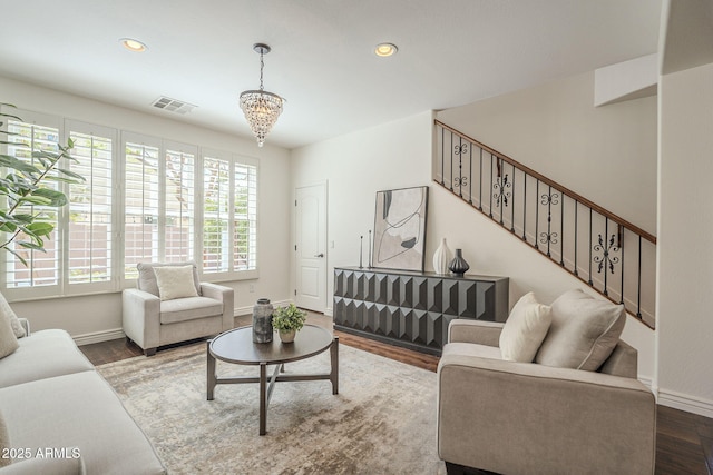 living room with stairs, a notable chandelier, wood finished floors, and visible vents