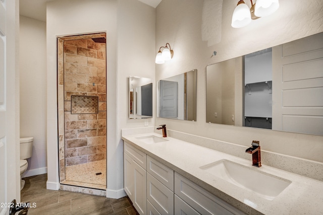 bathroom with toilet, a tile shower, and double vanity