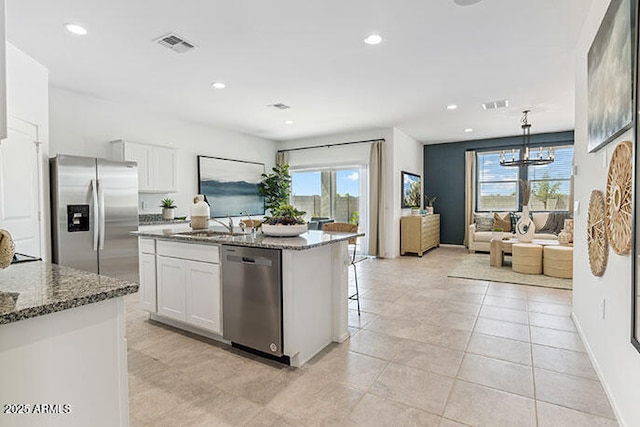 kitchen featuring white cabinetry, decorative light fixtures, stone countertops, and appliances with stainless steel finishes