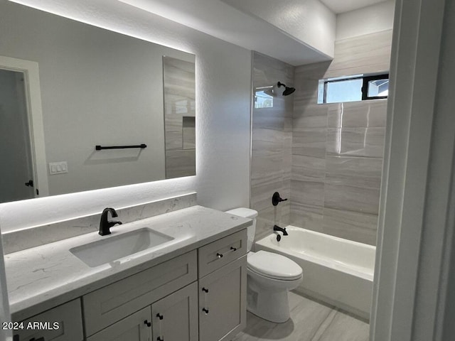 full bathroom featuring tiled shower / bath, vanity, and toilet