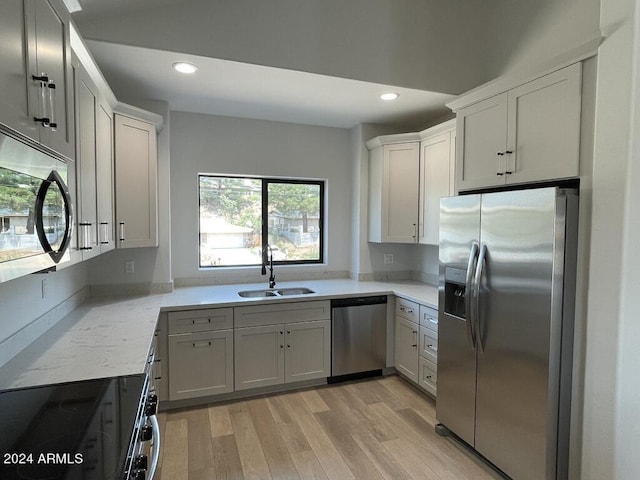 kitchen featuring sink, light hardwood / wood-style flooring, appliances with stainless steel finishes, light stone countertops, and white cabinets