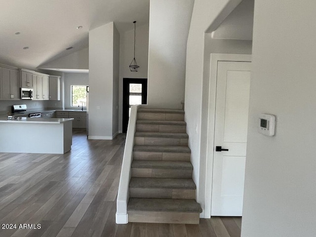 stairway featuring sink, hardwood / wood-style flooring, and vaulted ceiling