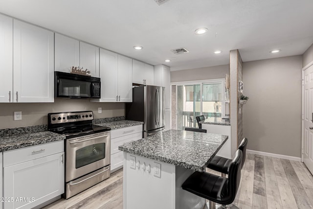 520 N Stapley Dr Unit 286, Mesa, AZ 85203 - kitchen featuring a breakfast bar, dark stone counters, visible vents, and appliances with stainless steel finishes