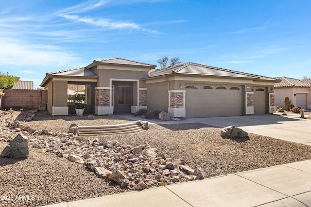 prairie-style house with a garage, concrete driveway, stone siding, fence, and stucco siding