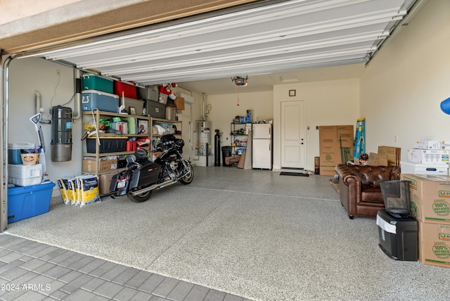 garage with gas water heater, white fridge, and a garage door opener