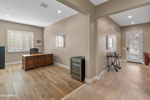 home office featuring light hardwood / wood-style flooring, plenty of natural light, and beverage cooler