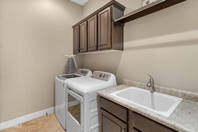 washroom featuring sink, light tile patterned flooring, washing machine and clothes dryer, and cabinets